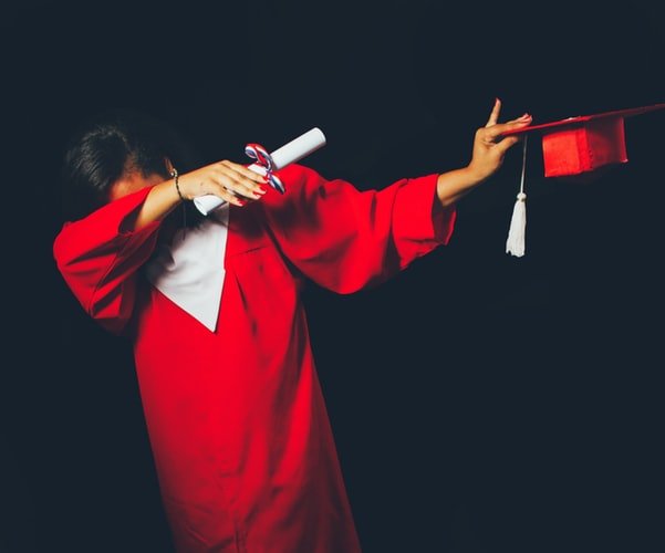 Pessoa com braços para o lado e beca de formatura