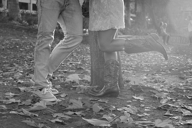 Pernas de cowboys em chão repleto de folhas