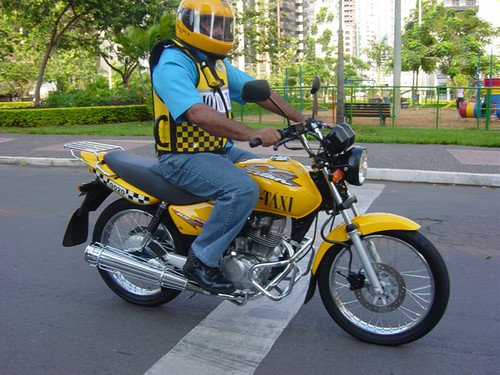 Homem pilotando moto, parado no farol