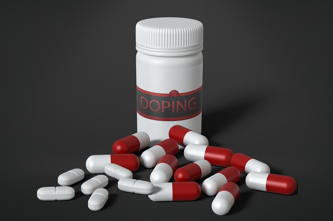 Recipiente escrito 'doping' ao lado de pílulas e cápsulas.