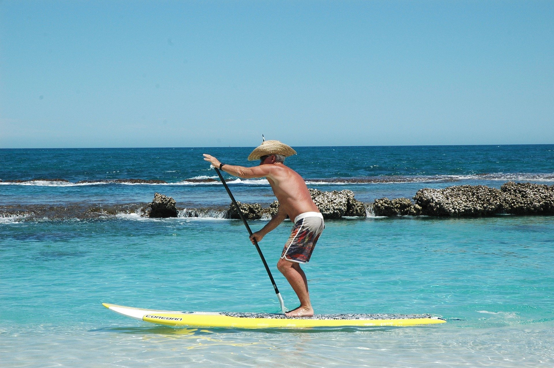 Idoso praticando em pé em prancha de surfe