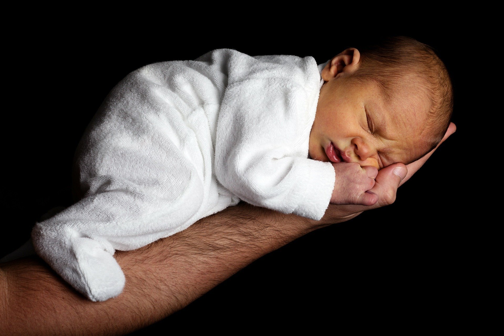 Bebê recém nascido dormindo deitado na mão do pai