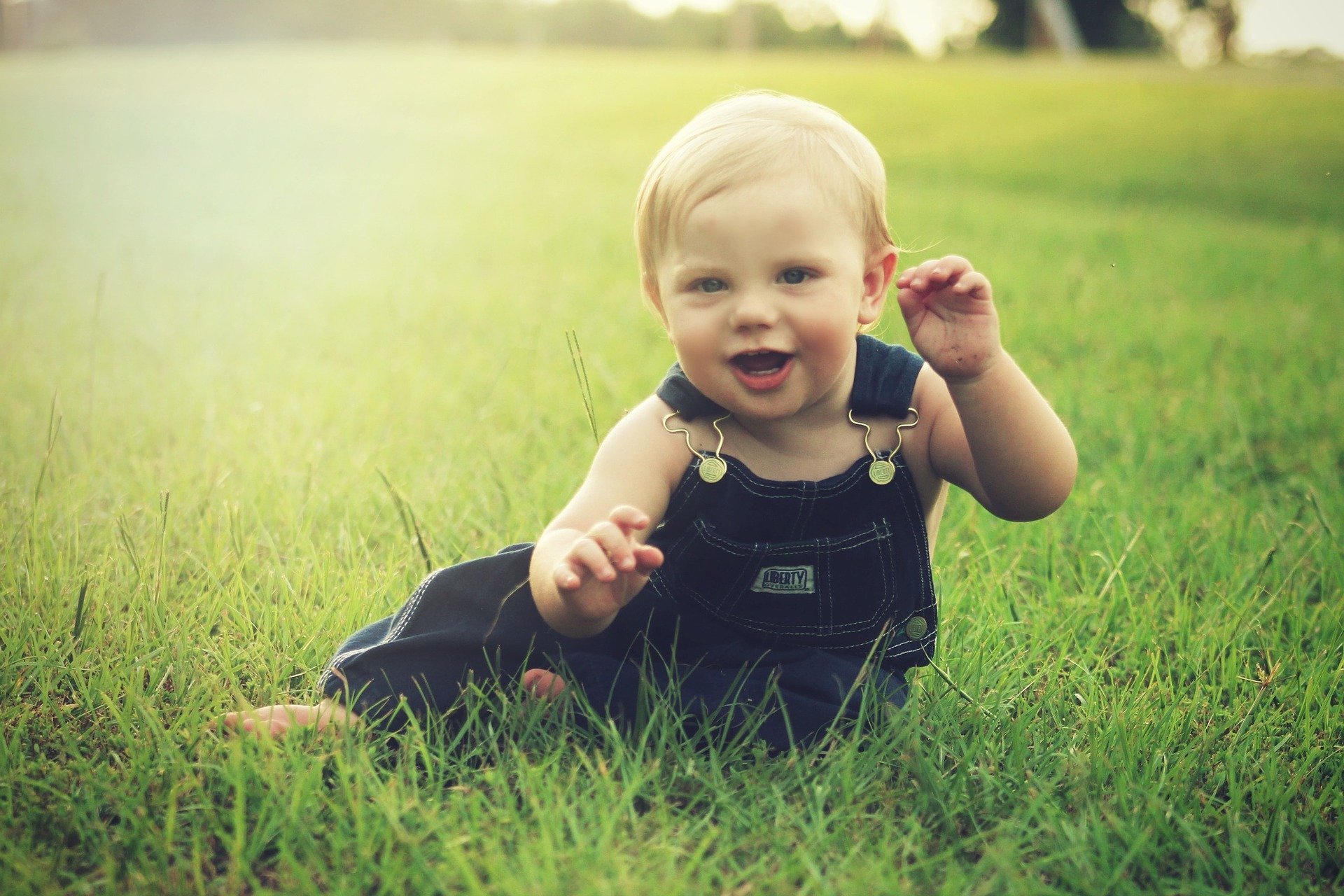 Bebê em campo usando macacão jeans