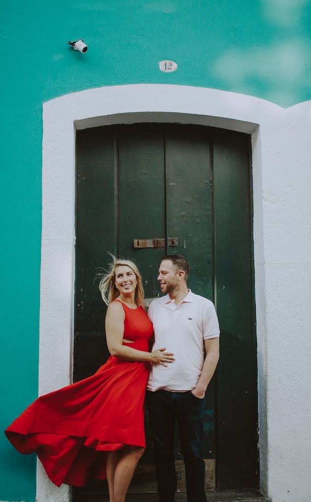 Casal abraçado em frente a uma porta antiga de madeira.