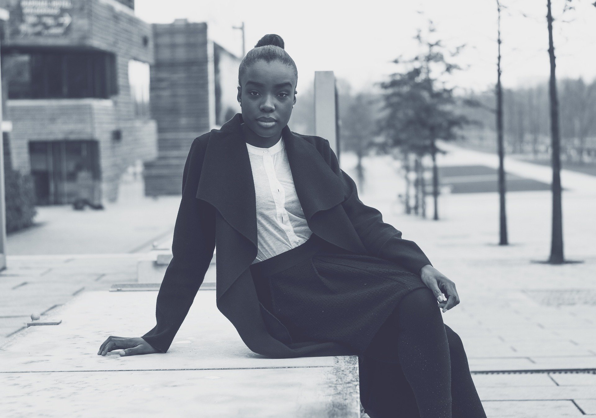 Foto de mulher negra sentada em banco na rua