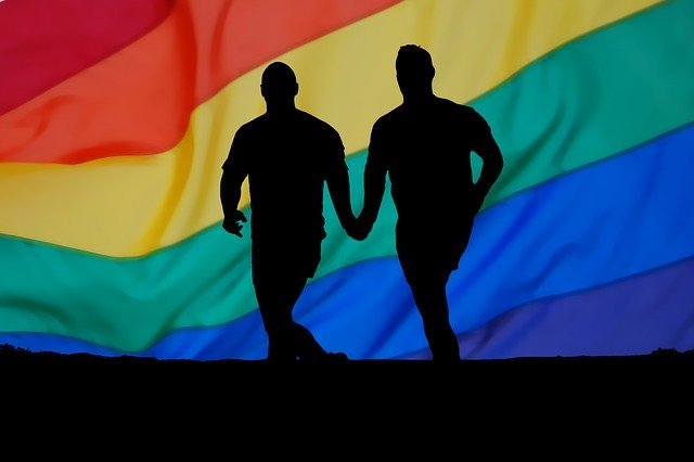 Casal homossexual e bandeira LGBT ao fundo