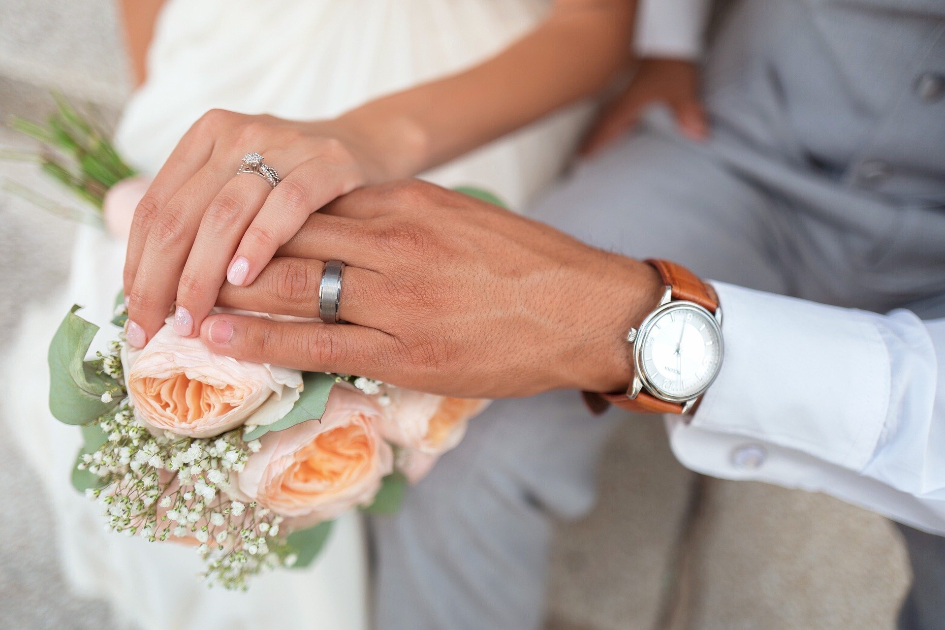 Foto de noivos mostrando suas mãos com alianças