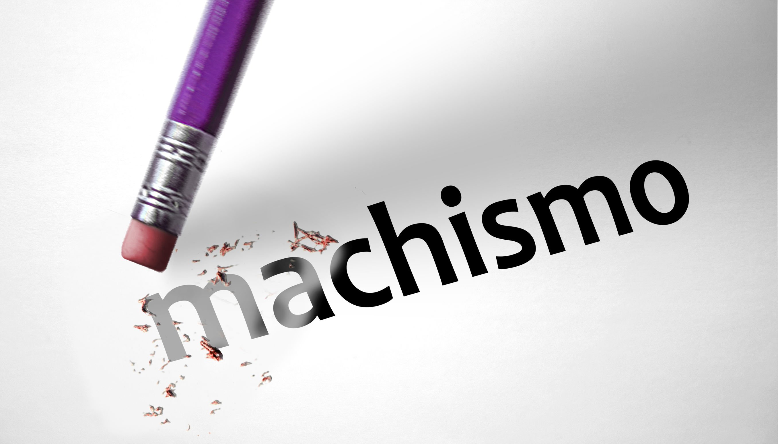 Palavra 'machismo' escrita em um papel, e um lápis de ponta cabeça, com sua borracha quase encostando no papel.