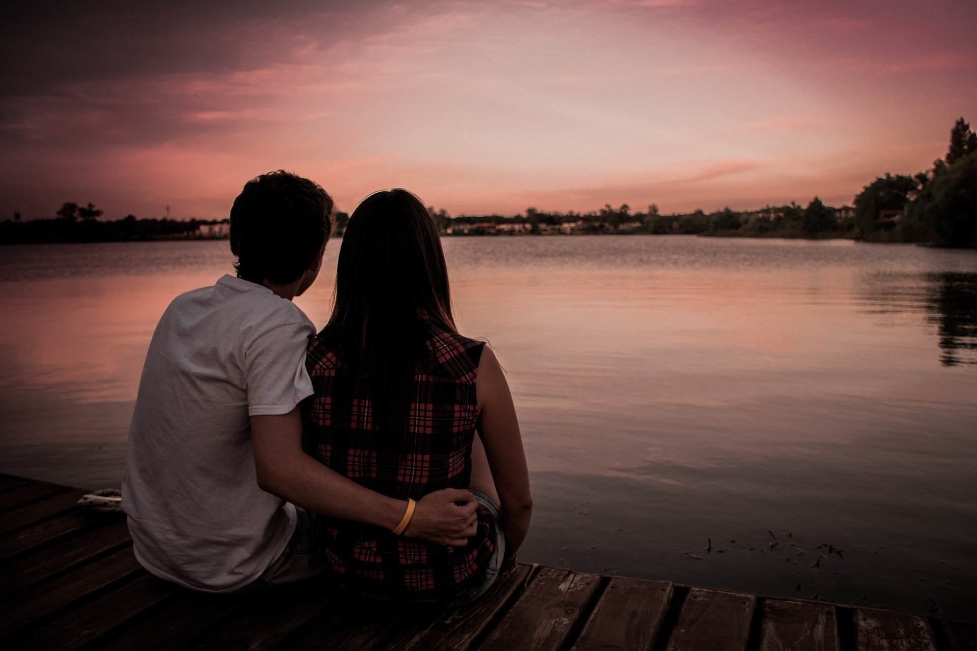 Imagem de casal sentado olhando lago