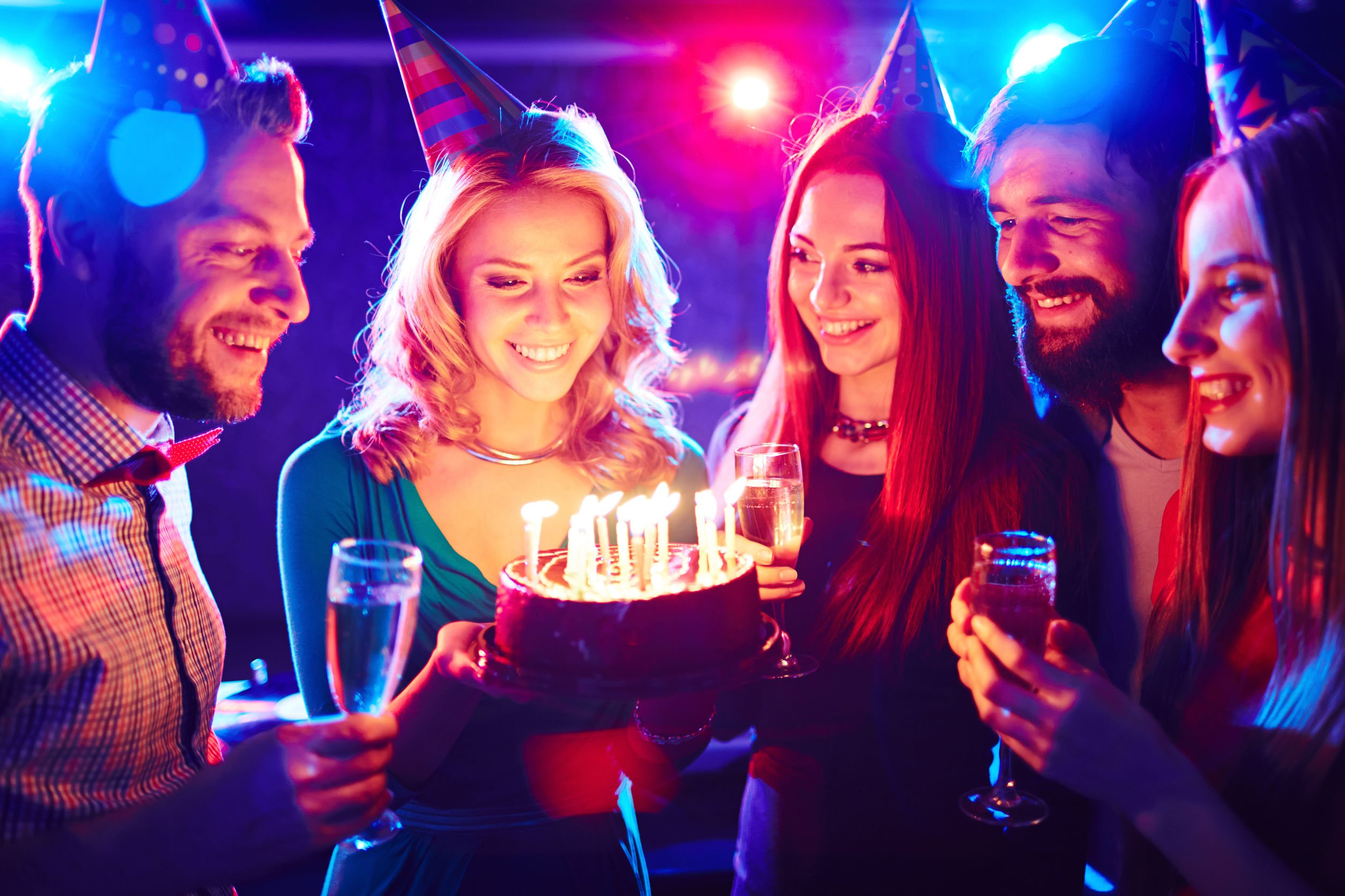 Pessoas comemorando aniversário ao redor de um bolo com velas acesas