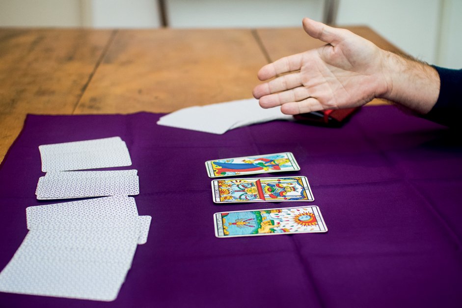 Taróloga com mão estendida e cartas de Tarot sobre pano roxo