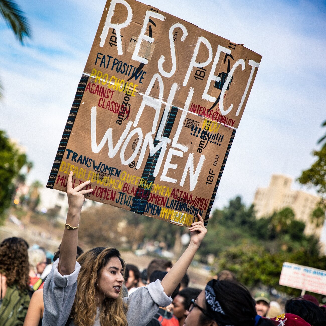 Mulher com um cartaz escrito em inglês 'respeite todas as mulheres'