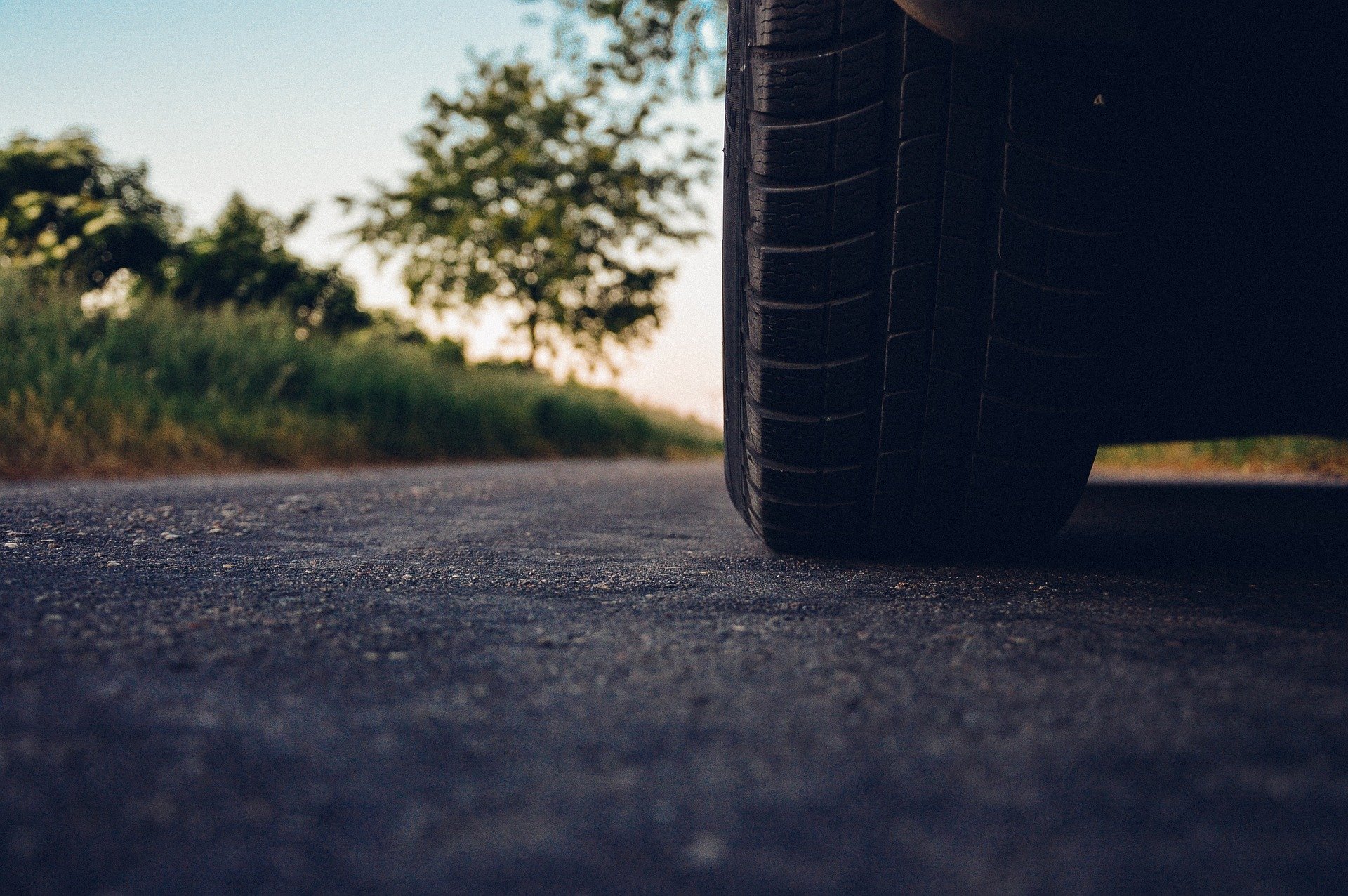 Foto periférica de carro em estrada, focando no pneu