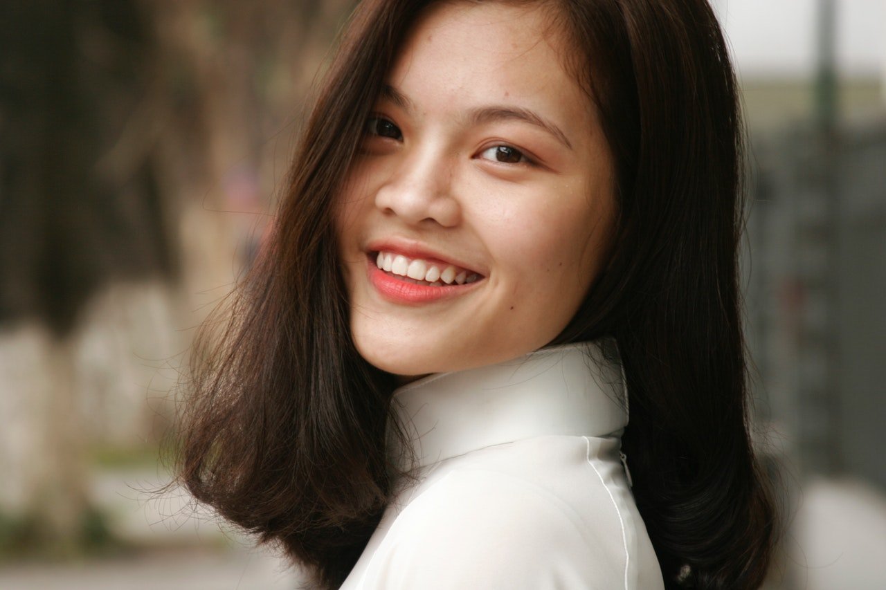 Mulher de traços sino-asiáticos sorrindo.