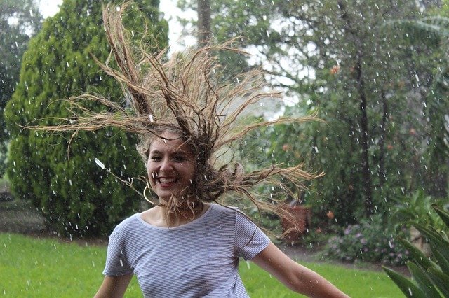 Mulher pulando em campo enquanto chove