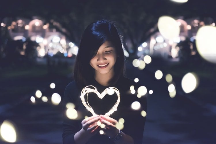 Menina asiática segurando coração luminoso