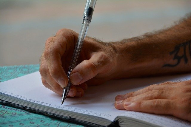 Braço masculino escrevendo em um caderno.