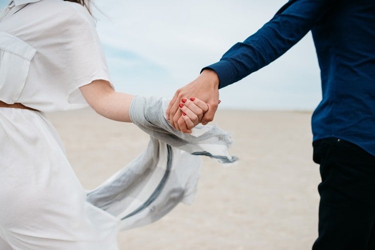 Casal de mãos dadas em praia
