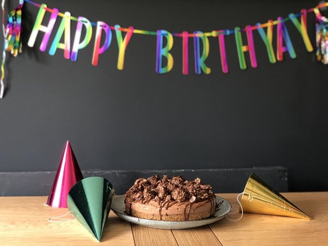 Bolo de aniversário com chapéus coloridos e Happy Birthday (feliz aniversário, em inglês) escrito em varal de letras