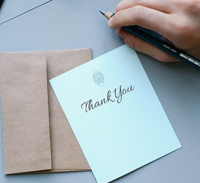 Pessoa com lápis na mão e papel escrito 'Thank You' (obrigado, em inglês)