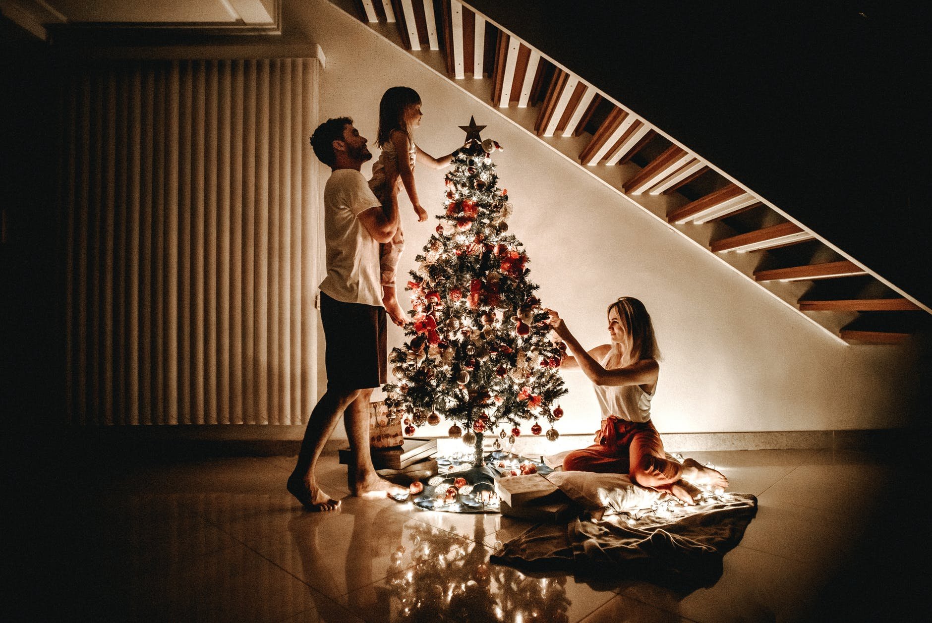 Homem e mulher com filha, montando árvore de natal