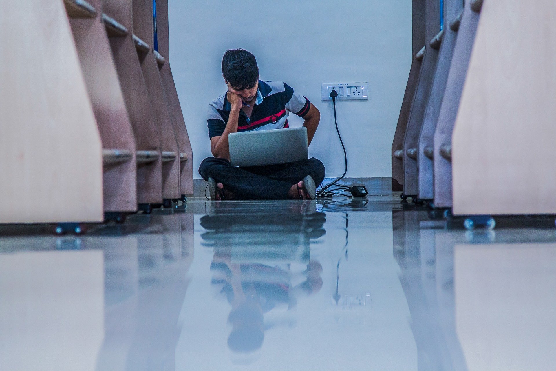 Adolescente mexendo em notebook sentado no chão