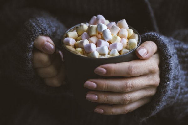 Tomasz Olszewski/Reshot Mulher segurando caneca com achocolatado e marshmallow coloridos