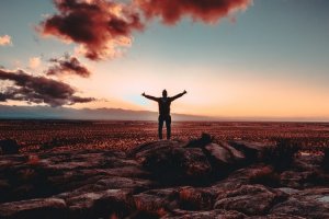 Unsplash/Xan Griffin Silhueta de pessoa sobre pedras de braços abertos