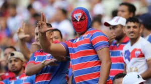 Homem torcedor do Fortaleza com o rosto pintado assistindo jogo no estádio