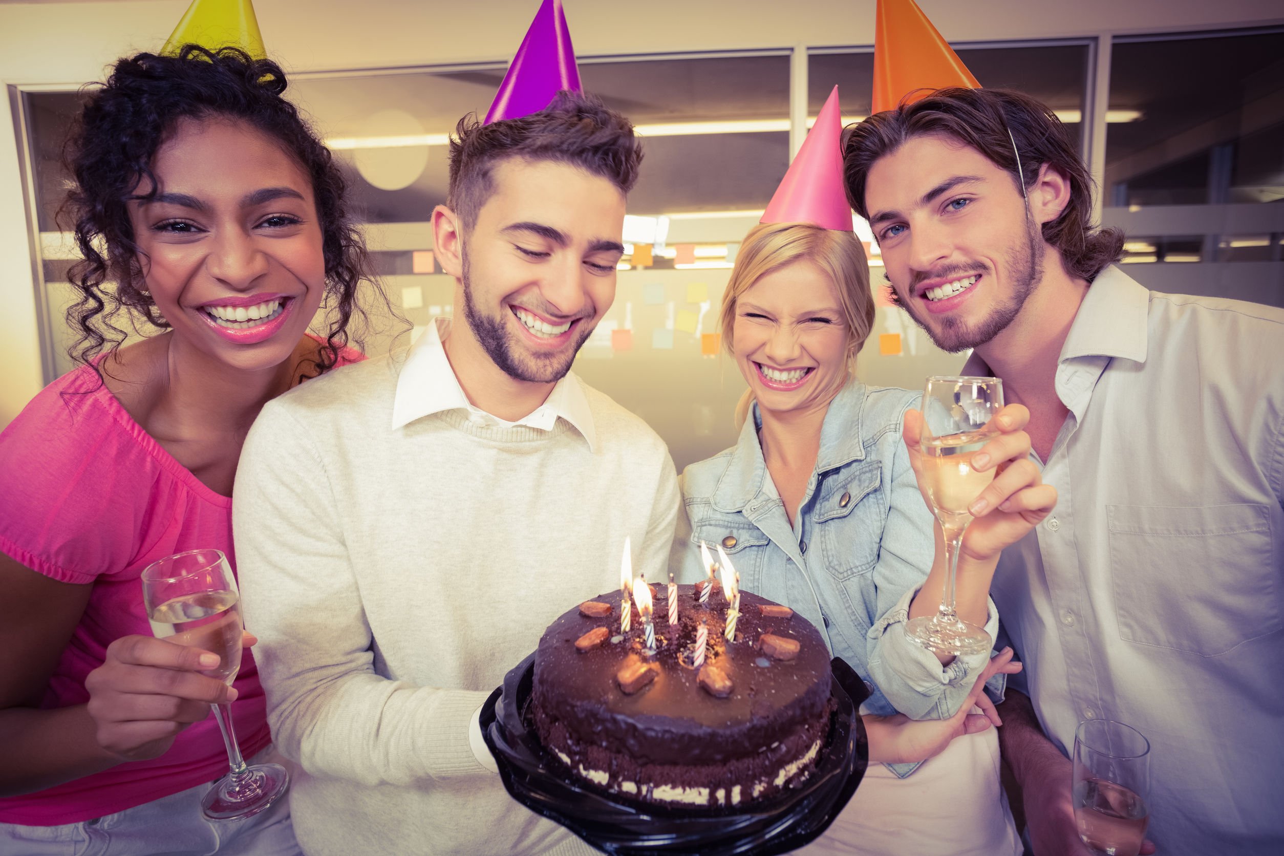 Pessoas comemorando aniversário em volta de bolo de aniversário com velas acesas