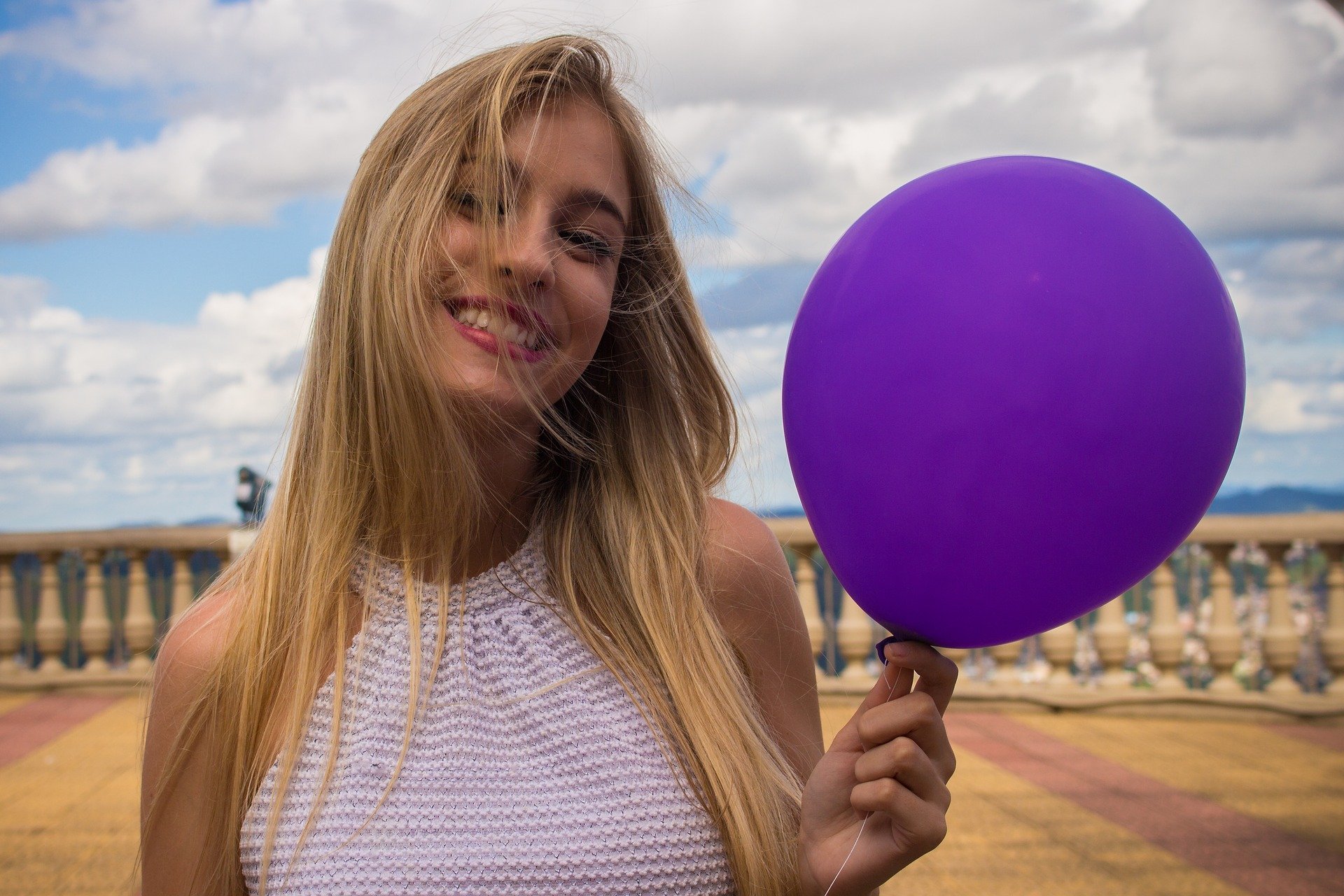 Mulher segurando balão roxo enquanto sorri