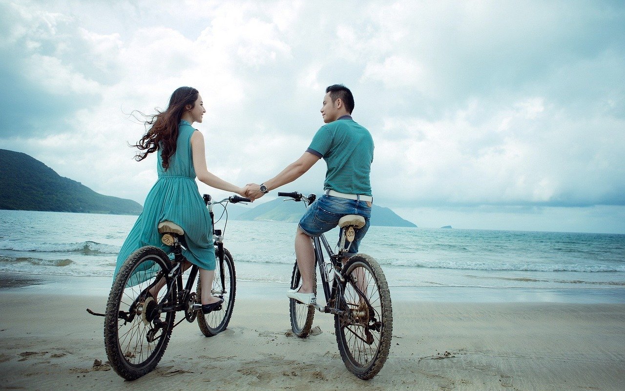 Casal andando de bicicleta em praia