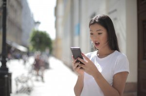 Pexels/Andrea Piacquadio Mulher de boca aberta olhando para seu celular.
