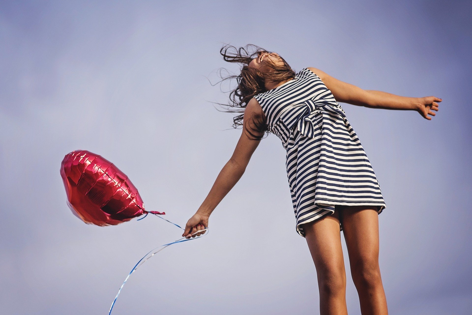 Mulher feliz segurando balão de braços abertos
