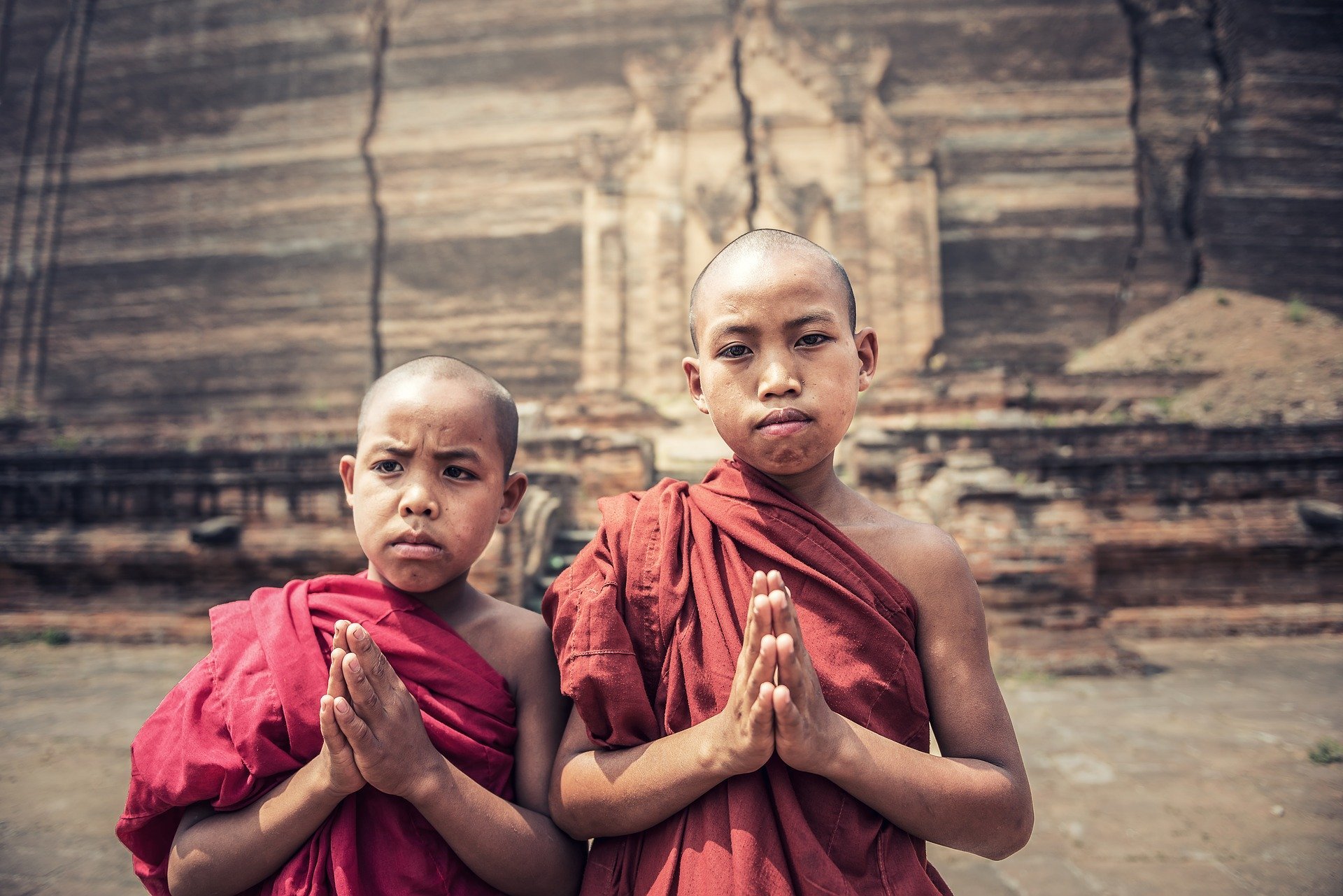 Meninos com as cabeças raspadas e vestes de monge com as mãos unidas em sinal de oração