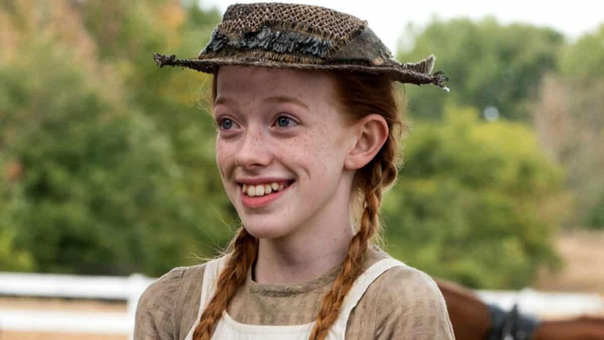 Personagem da série Anne with an E sorrindo usando chapéu
