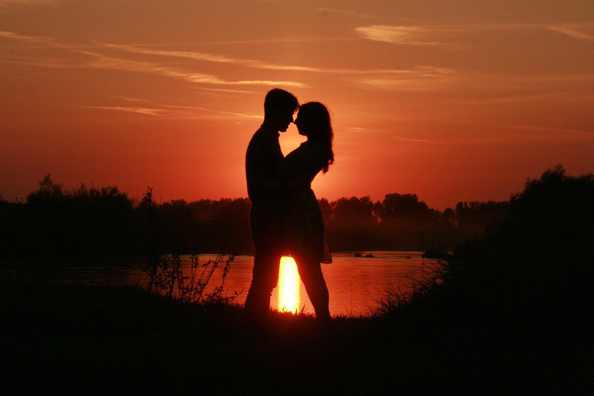 Pixabay Silhueta de casal frente à frente em pôr do sol perto de lago