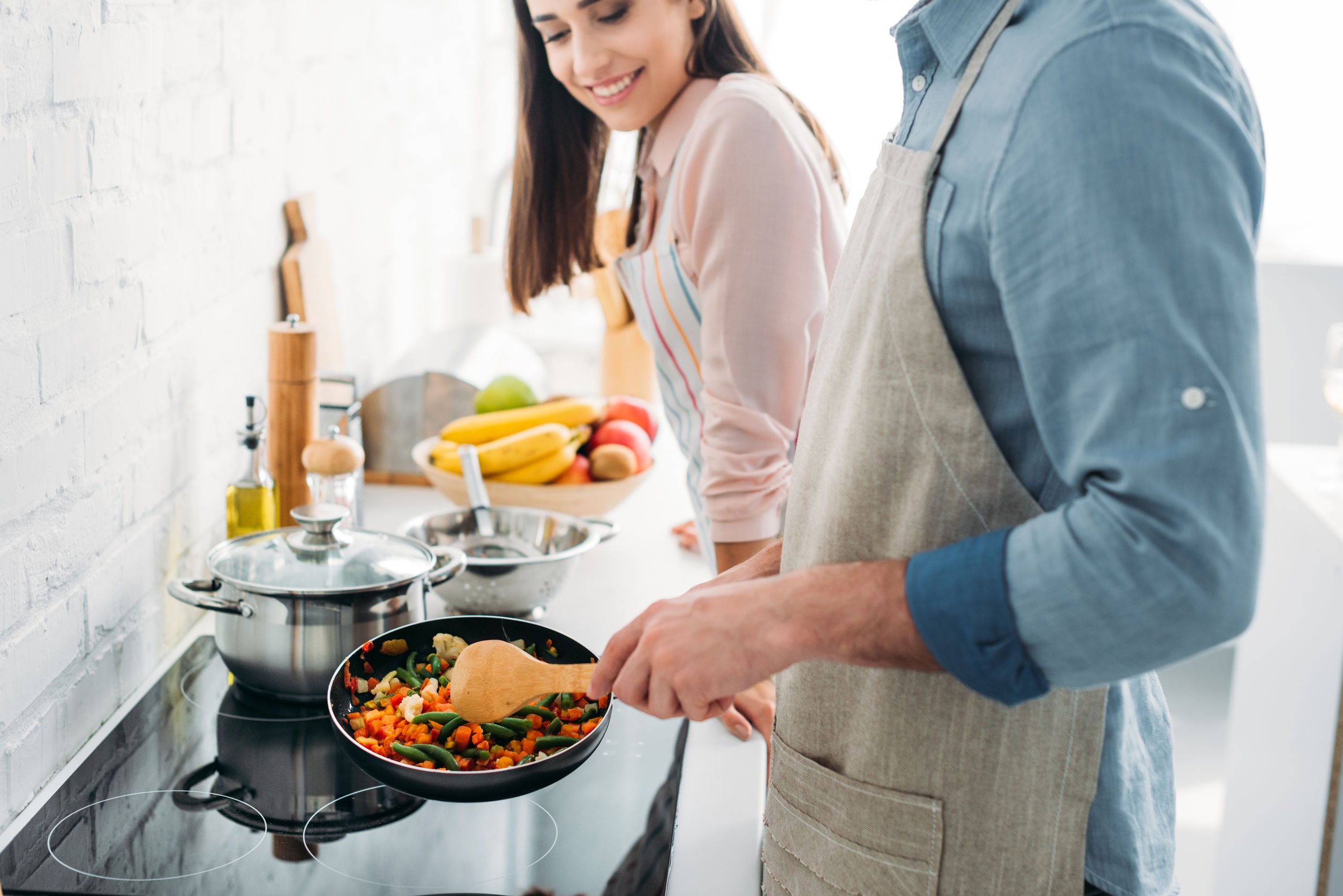 Homem e mulher cozinhando café da manhã em cozinha