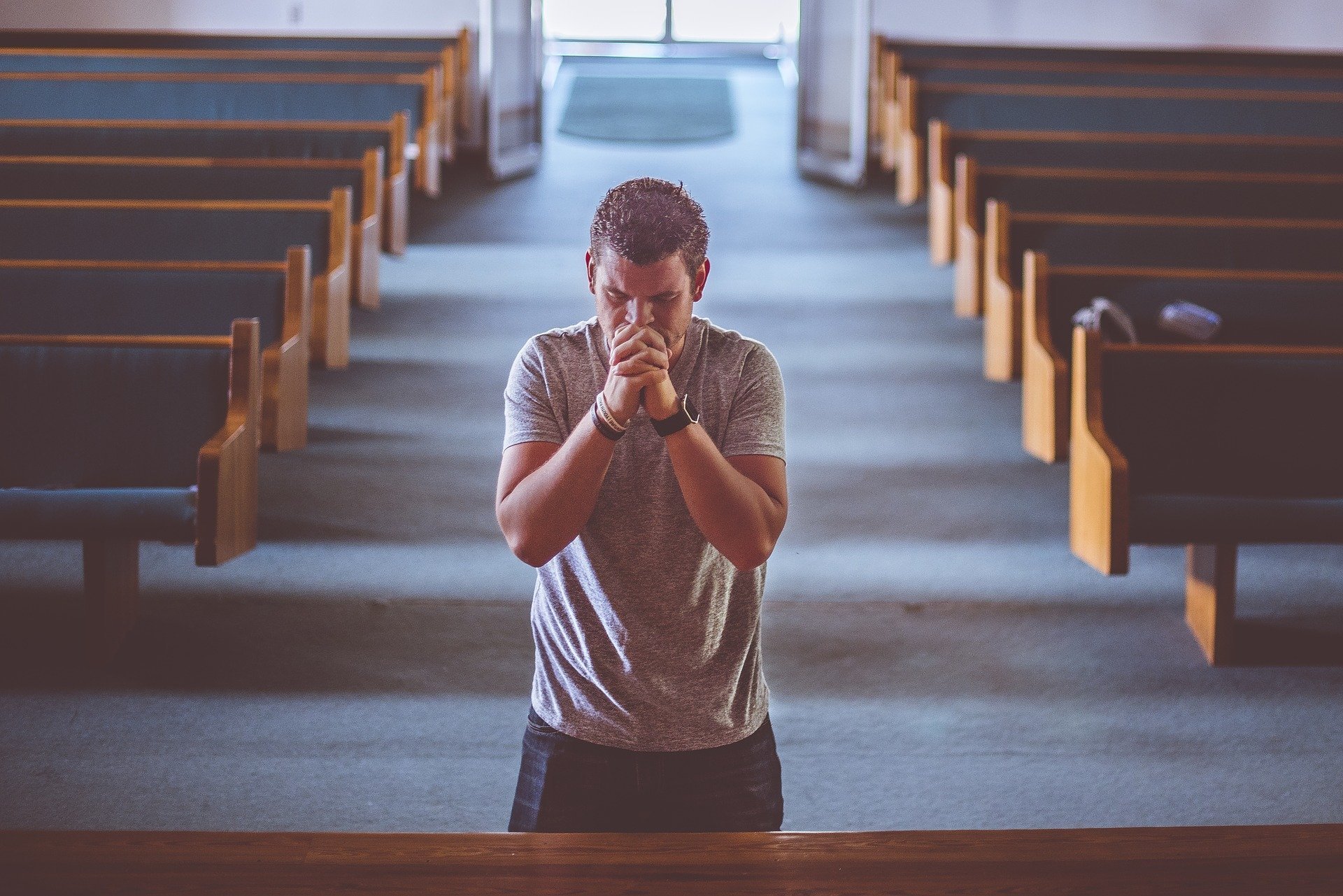 Homem ajoelhado orando em altar de igreja
