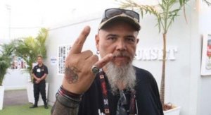 Reprodução/ Jornal da record João Gordo usando boné, fazendo sinal do rock com uma das mãos