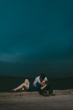Unsplash Homem e mulher se beijando sentados em calçada