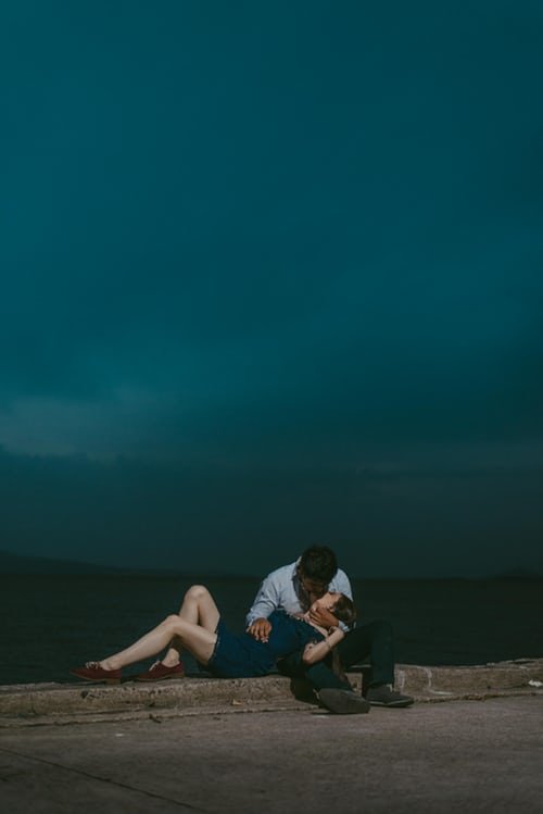 Homem e mulher se beijando sentados em calçada