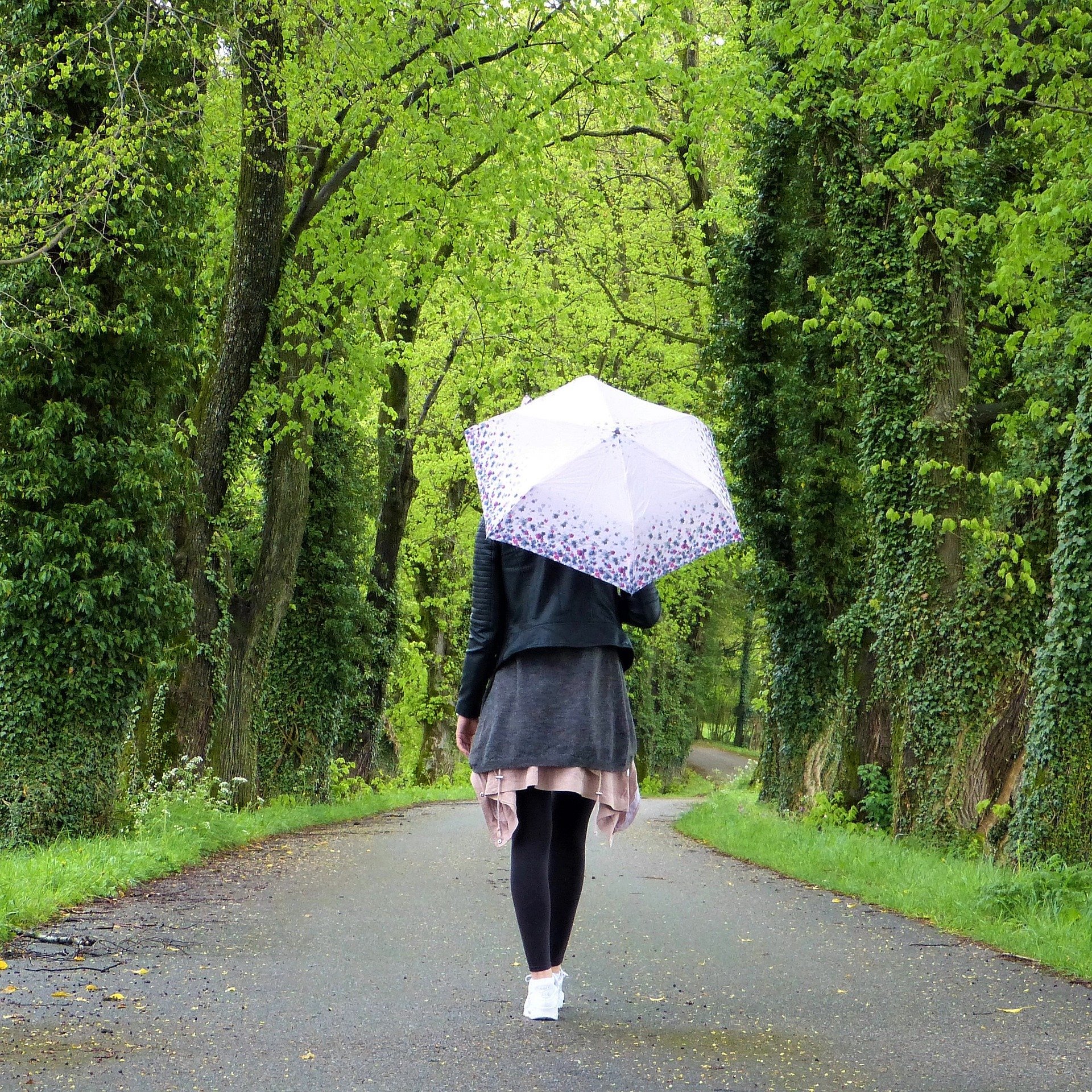 Mulher andando em parque segurando guarda chuva