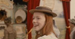 Reprodução/ Omelete Personagem principal da série Anne with an E usando chapéu, sorrindo