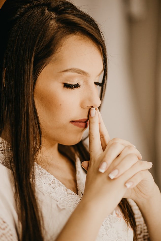 Unsplash Mulher orando apoiando o rosto em suas mãos unidos