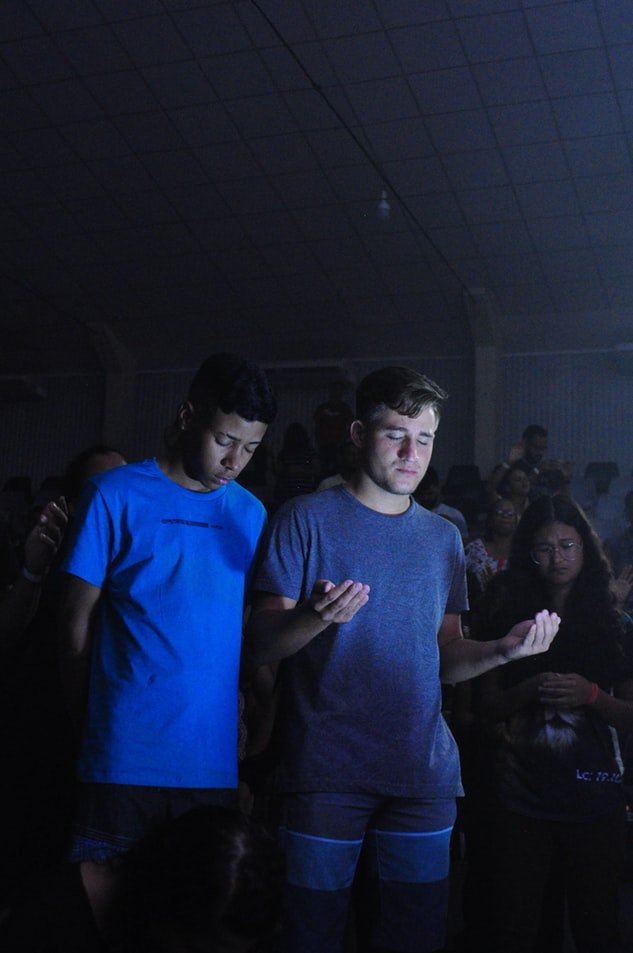 Meninos orando em pé no meio de culto