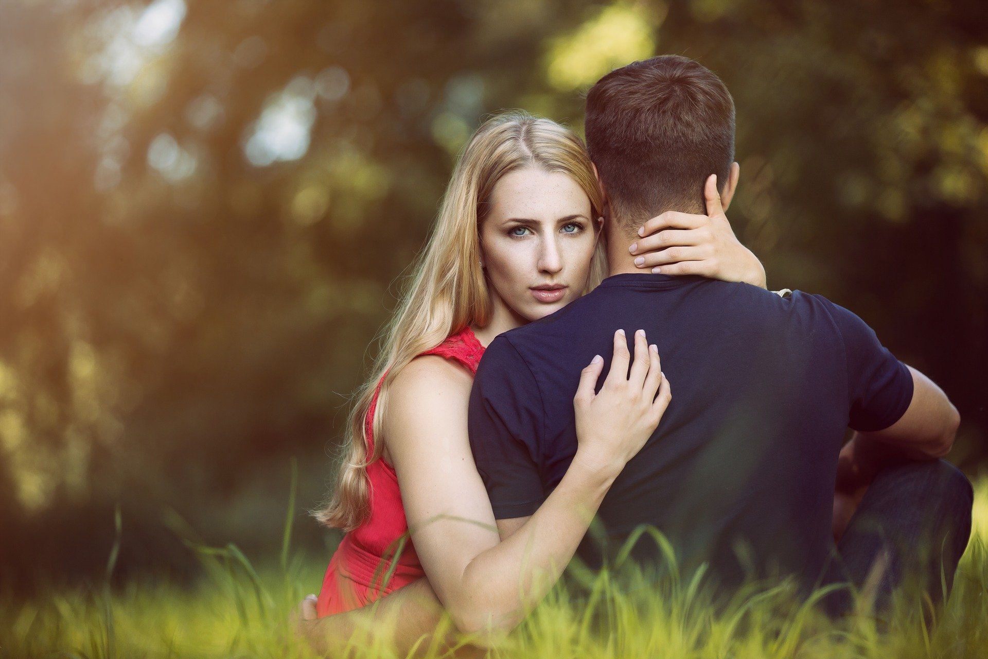 Homem e mulher se abraçando sentados em grama