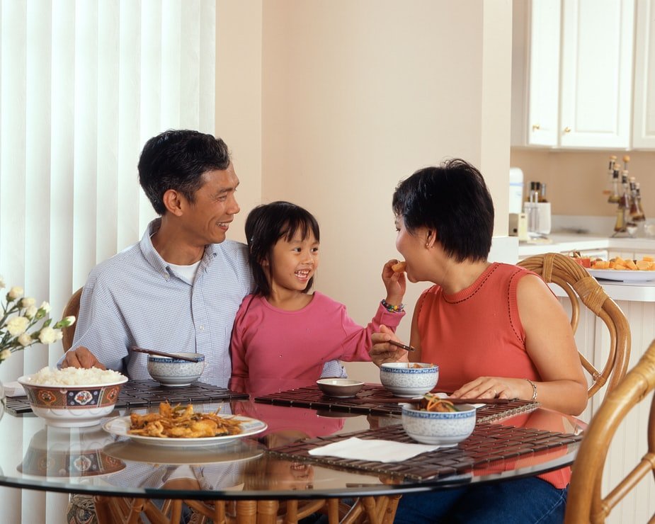 Família comendo sentados em mesa de jantar