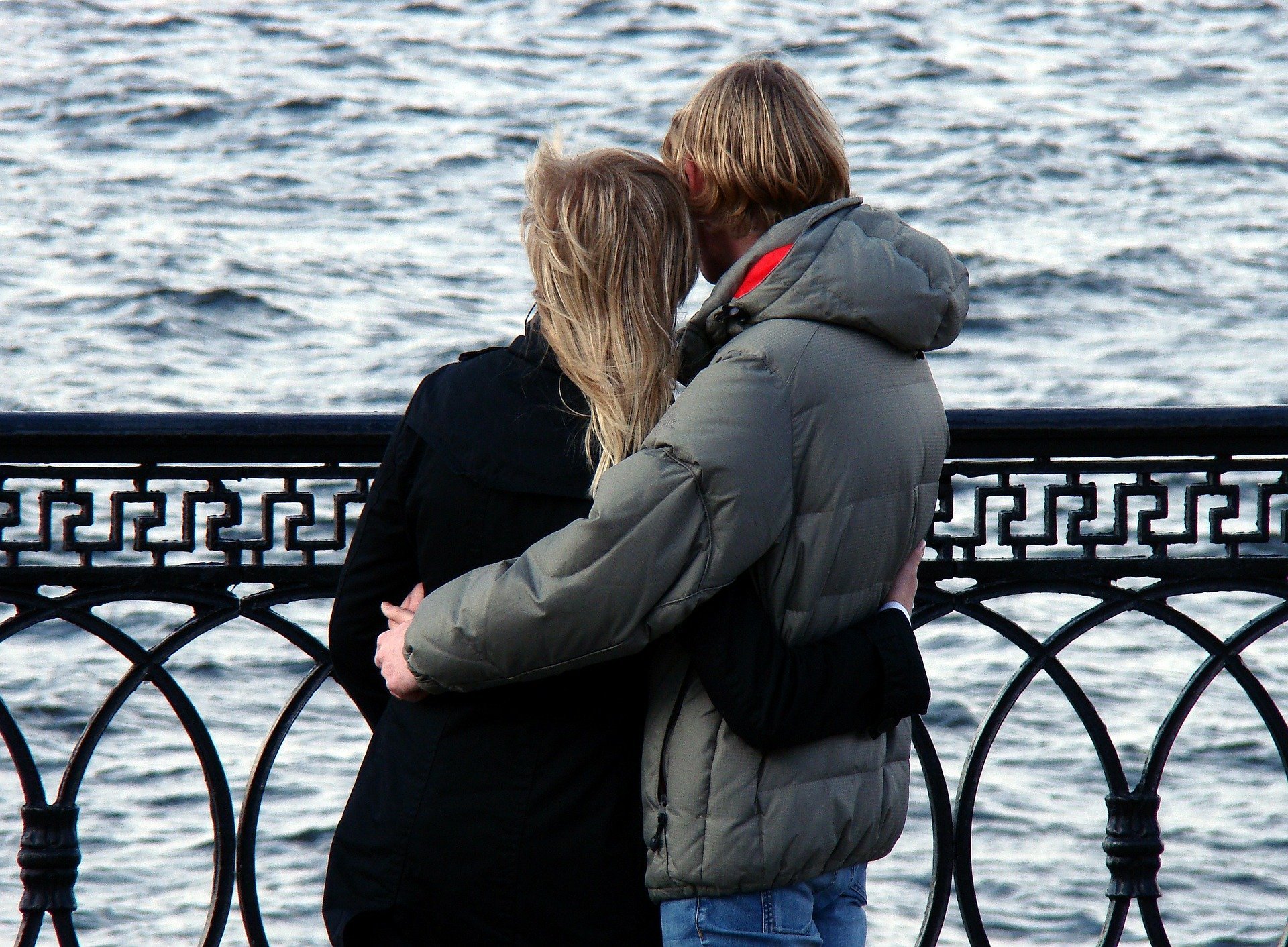 Casal se abraçando e olhando para mar