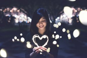 Unsplash Mulher sorrindo segurando fio de luzes em formato de coração